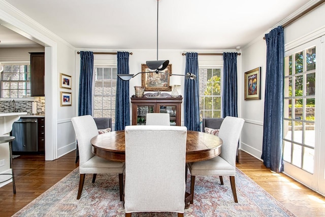 dining space with a healthy amount of sunlight, wood finished floors, and ornamental molding