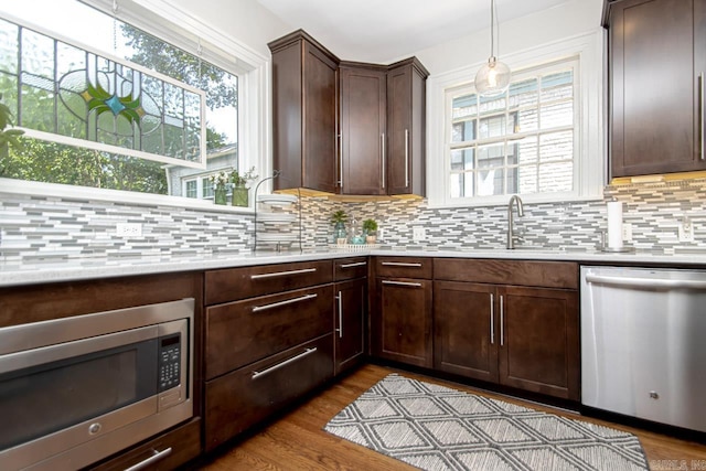 kitchen with decorative backsplash, plenty of natural light, wood finished floors, and appliances with stainless steel finishes