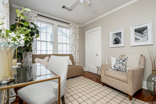 sitting room with wood finished floors, baseboards, visible vents, ceiling fan, and ornamental molding