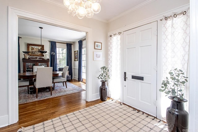 entrance foyer with wood finished floors, baseboards, a chandelier, and ornamental molding