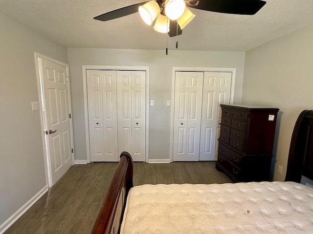 bedroom featuring baseboards, two closets, dark wood-style flooring, and a textured ceiling