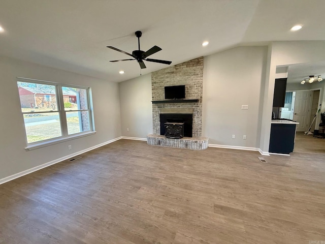 unfurnished living room featuring visible vents, baseboards, vaulted ceiling, wood finished floors, and a ceiling fan