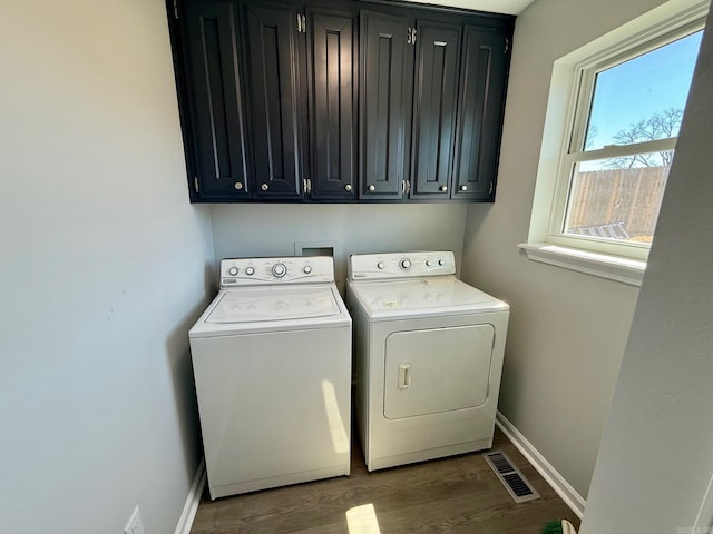 laundry room featuring visible vents, wood finished floors, washing machine and dryer, cabinet space, and baseboards