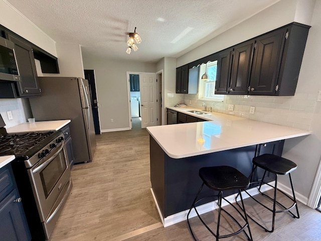 kitchen with a sink, stainless steel appliances, light wood-style flooring, and light countertops