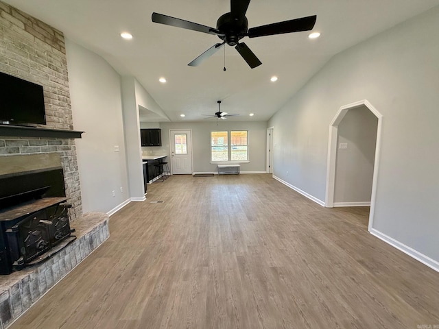 unfurnished living room with baseboards, lofted ceiling, and wood finished floors