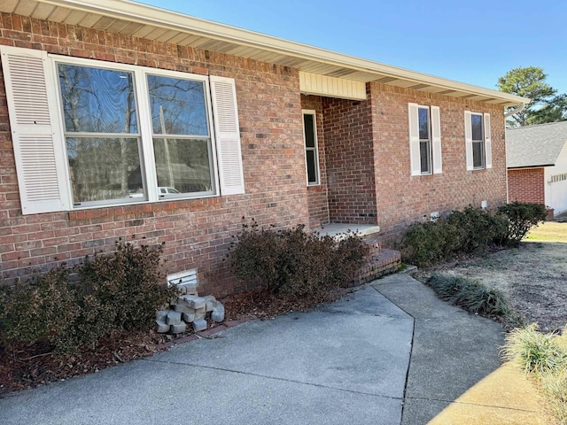 view of exterior entry with crawl space and brick siding