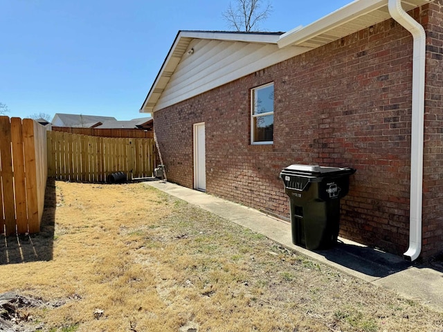 view of property exterior with fence and brick siding