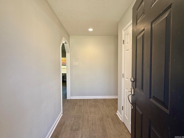 corridor with baseboards, recessed lighting, arched walkways, dark wood-style flooring, and a textured ceiling