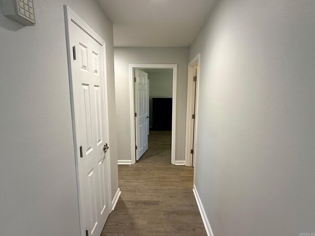 corridor with baseboards and dark wood-style floors