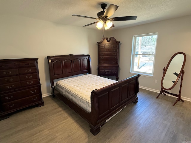 bedroom with ceiling fan, baseboards, a textured ceiling, and wood finished floors