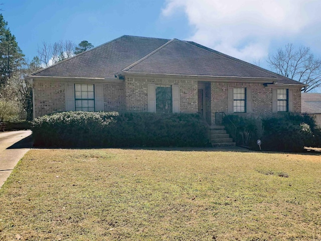 ranch-style home with brick siding, a shingled roof, and a front lawn