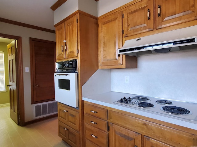 kitchen featuring visible vents, brown cabinets, under cabinet range hood, white appliances, and light countertops