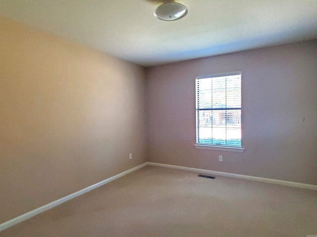 spare room with visible vents, light colored carpet, and baseboards