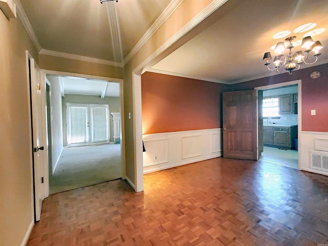 interior space with visible vents, a wainscoted wall, an inviting chandelier, a sink, and crown molding