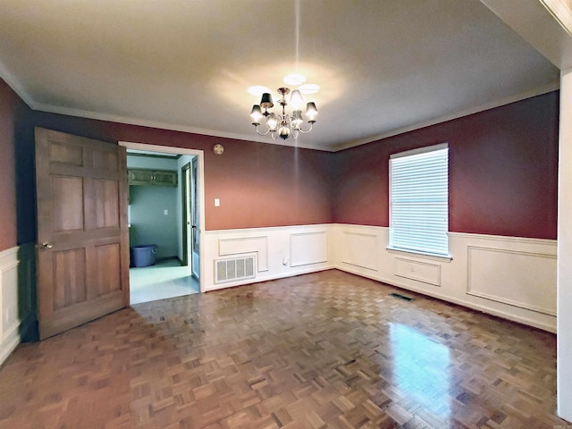 empty room with visible vents, a wainscoted wall, and a chandelier