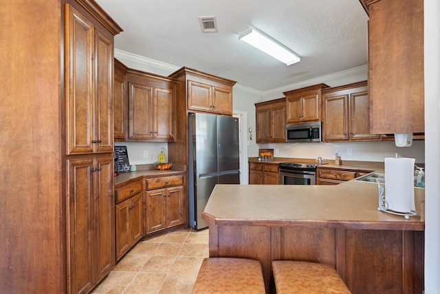 kitchen with brown cabinets, appliances with stainless steel finishes, a peninsula, and crown molding