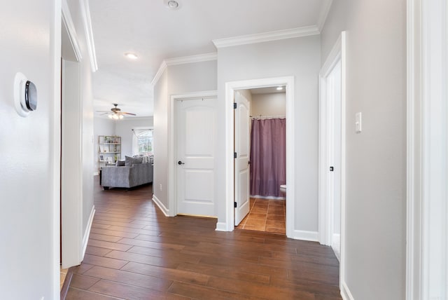 hallway featuring ornamental molding, baseboards, and dark wood-style flooring