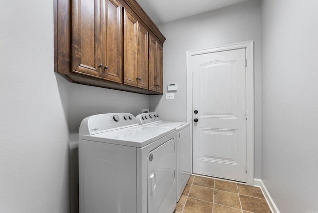 clothes washing area with washing machine and clothes dryer, cabinet space, tile patterned floors, and baseboards