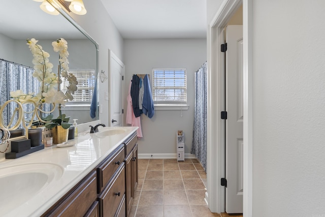 bathroom with tile patterned floors, double vanity, baseboards, and a sink