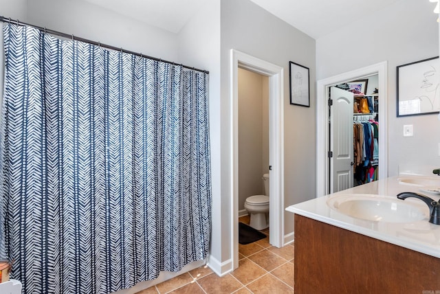 bathroom featuring tile patterned flooring, double vanity, toilet, and a sink