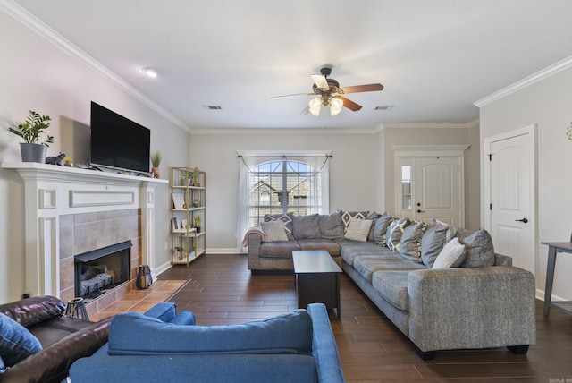 living room featuring baseboards, visible vents, wood finish floors, a tile fireplace, and ornamental molding