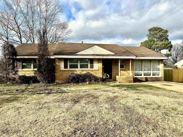 single story home featuring a front yard, fence, and brick siding