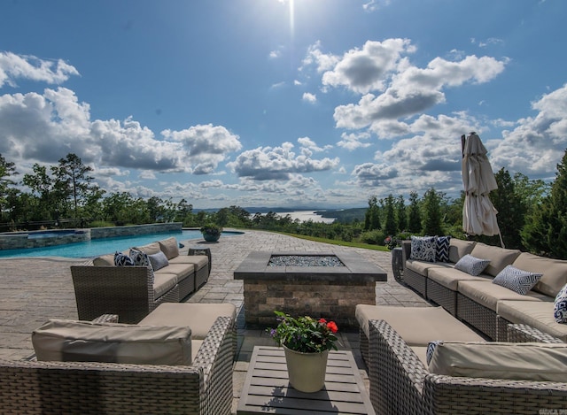 view of patio / terrace with area for grilling, an outdoor living space with a fire pit, and an infinity pool