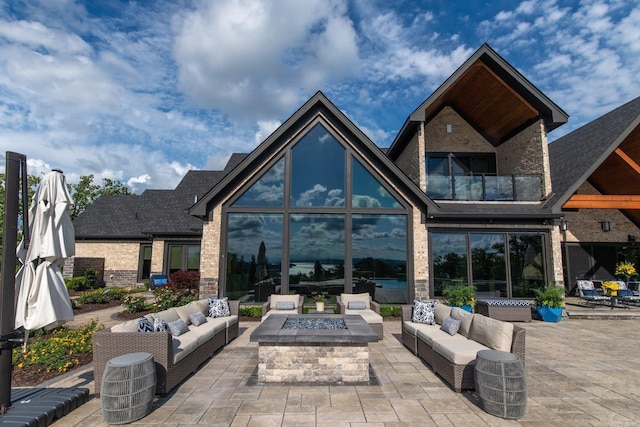 rear view of property with an outdoor living space with a fire pit, a patio area, and brick siding