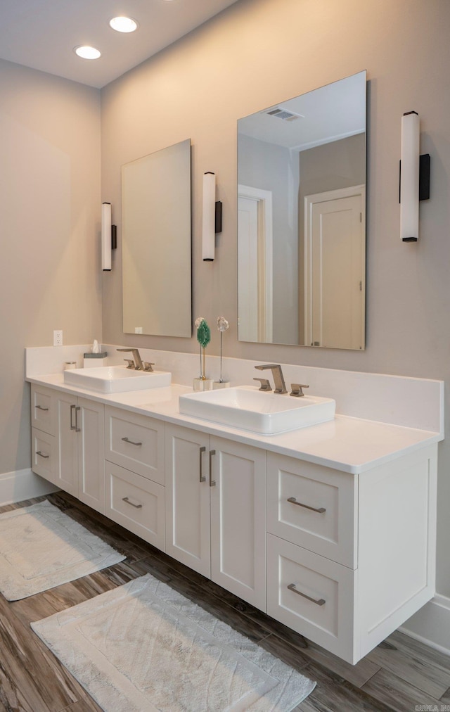 bathroom with double vanity, wood finished floors, and a sink