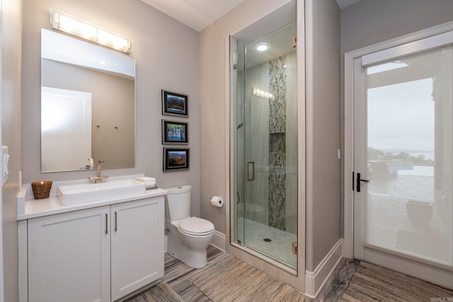 full bath with a shower stall, toilet, vanity, and baseboards