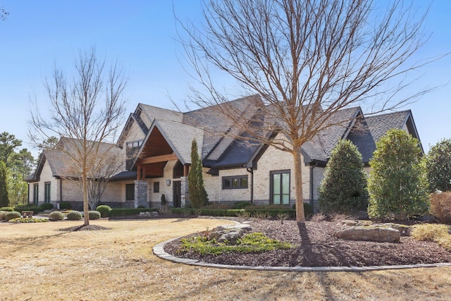 view of front of home featuring brick siding, stone siding, and roof with shingles