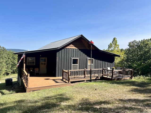 back of property with a wooden deck, central AC unit, a yard, and board and batten siding