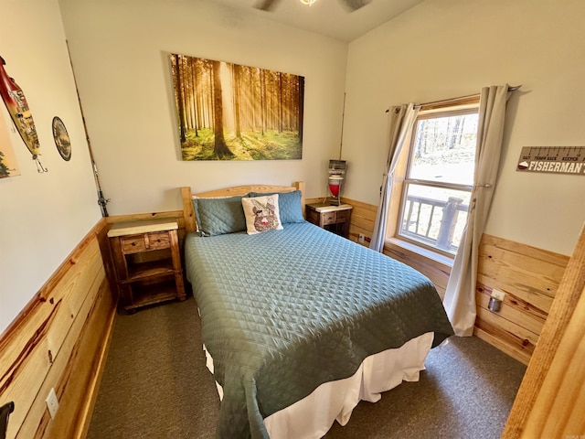 bedroom with a wainscoted wall, carpet floors, wood walls, and vaulted ceiling