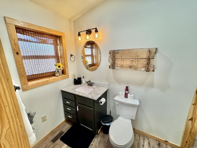 bathroom featuring visible vents, toilet, wood finished floors, baseboards, and vanity