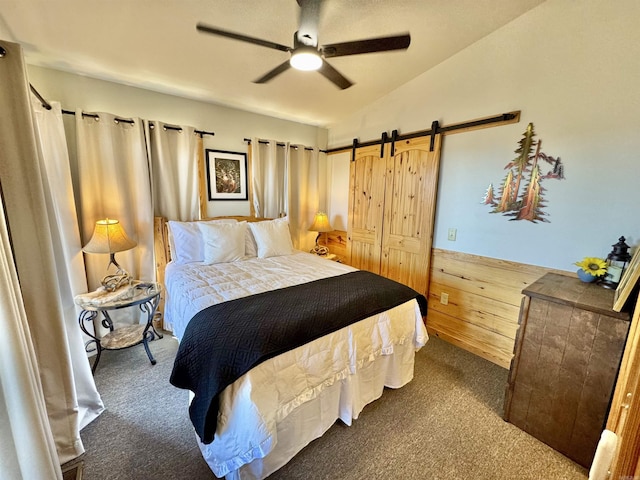 carpeted bedroom with ceiling fan, a barn door, and vaulted ceiling