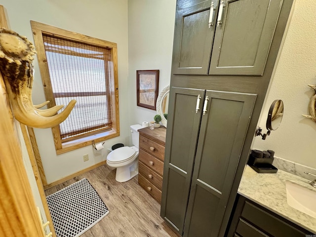 bathroom with vanity, toilet, wood finished floors, and baseboards