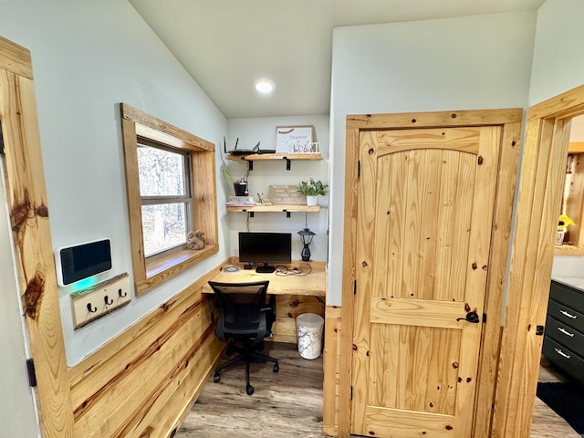 office featuring vaulted ceiling, built in desk, and wood finished floors