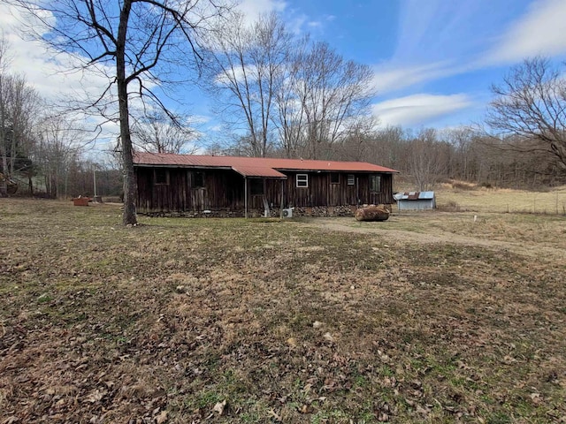 view of front of home with board and batten siding, metal roof, and a front lawn