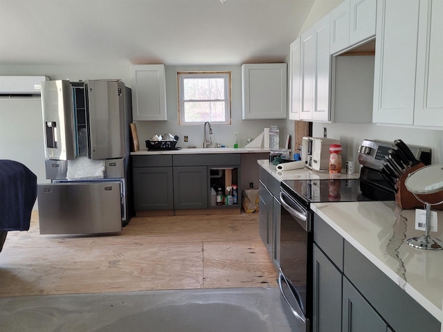 kitchen with stainless steel electric range oven, light countertops, gray cabinets, and a sink