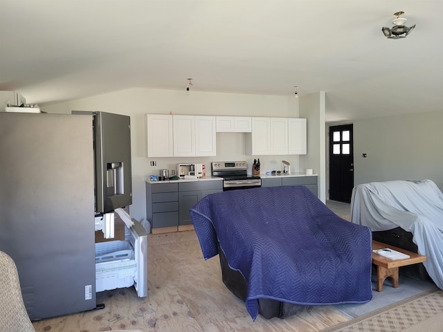 kitchen with light countertops, white cabinets, vaulted ceiling, and stainless steel appliances