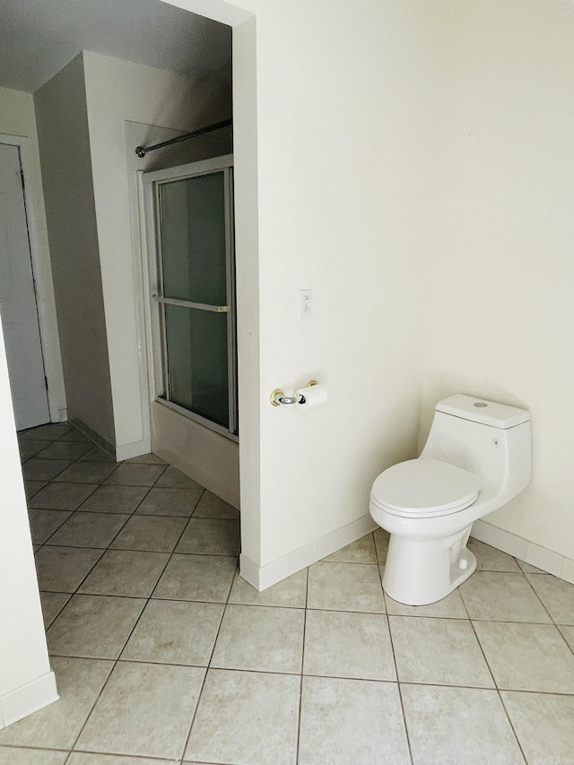 full bathroom featuring tile patterned flooring, toilet, baseboards, and combined bath / shower with glass door