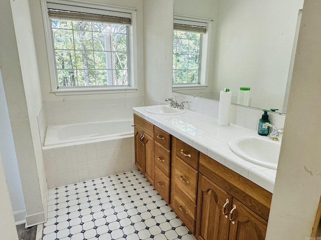 bathroom featuring a sink, double vanity, and tiled bath