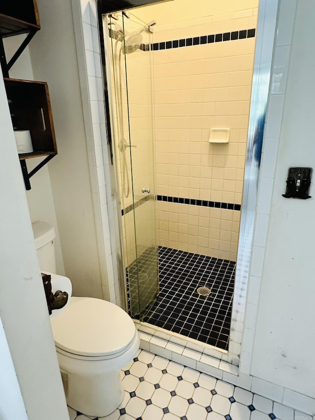 bathroom featuring a shower stall, toilet, and tile patterned floors