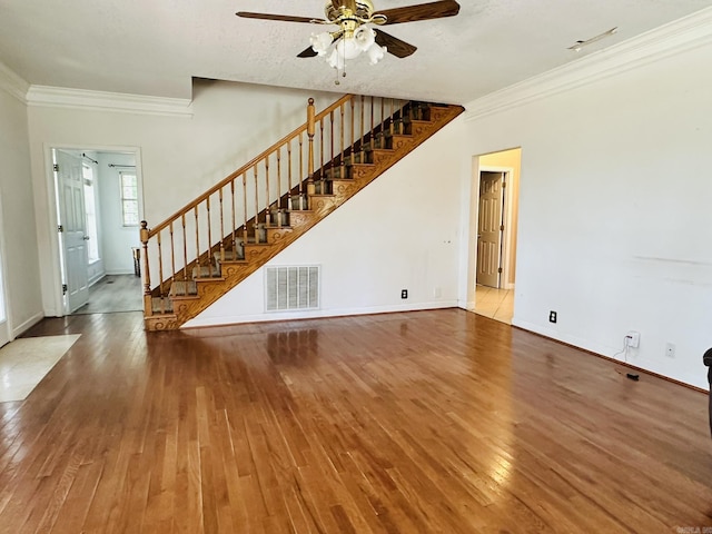 unfurnished living room with visible vents, stairway, crown molding, and hardwood / wood-style floors