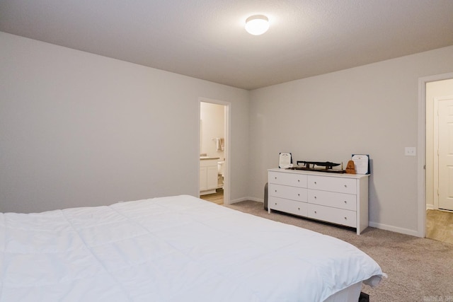 bedroom featuring light carpet, connected bathroom, and baseboards