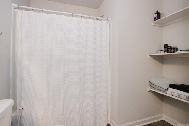 bathroom with curtained shower, baseboards, and toilet