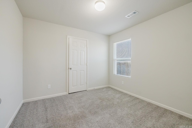 carpeted spare room with visible vents and baseboards