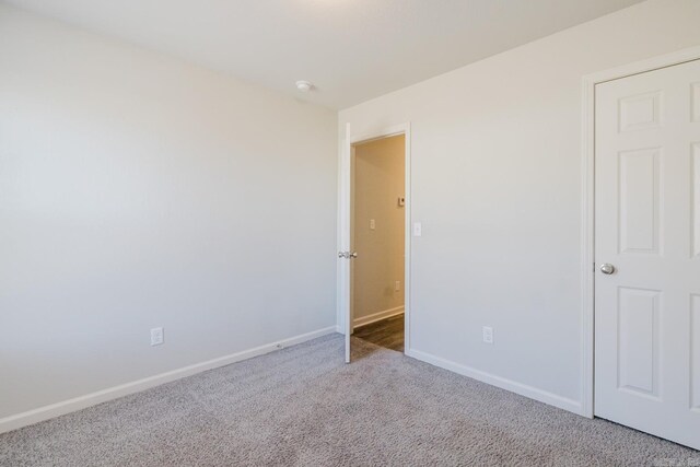 unfurnished room with carpet flooring and baseboards