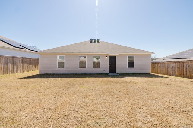 rear view of property with a lawn and a fenced backyard