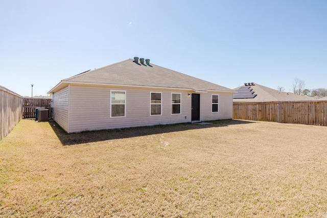 rear view of house featuring central air condition unit, a yard, and a fenced backyard